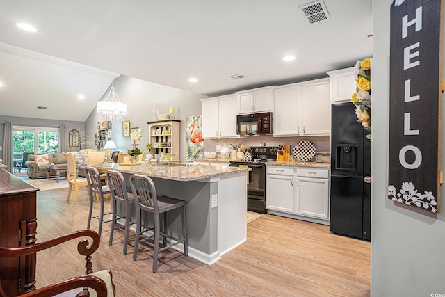 2016 Willow Run Dr Unit B, Little River, SC 29566 - kitchen with black appliances, light wood-type flooring, white cabinets, a breakfast bar, and lofted ceiling