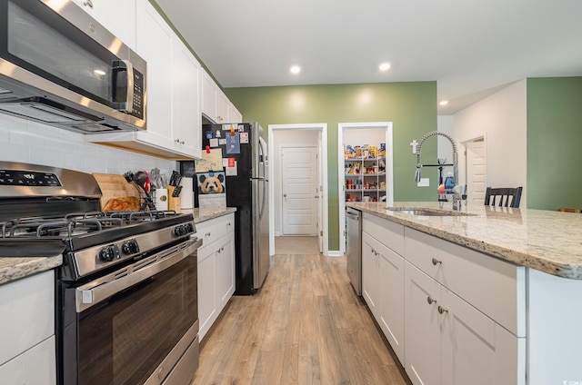 787 Dusty Pine Way, Myrtle Beach, SC 29588 - kitchen with stainless steel appliances, a sink, white cabinets, light wood-style flooring, and decorative backsplash