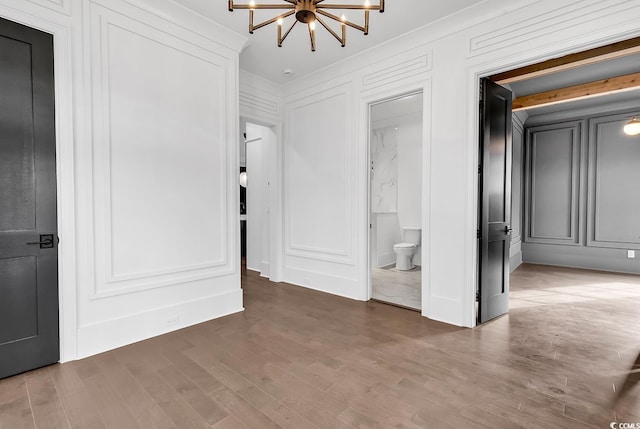 437 Saint Julian Ln, Myrtle Beach, SC 29579 - unfurnished bedroom with a decorative wall, a chandelier, wood finished floors, ornamental molding, and connected bathroom