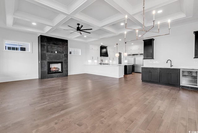 437 Saint Julian Ln, Myrtle Beach, SC 29579 - unfurnished living room with beverage cooler, wood finished floors, beamed ceiling, a tiled fireplace, and coffered ceiling