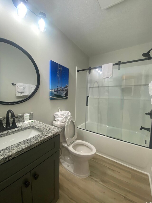 6205 Nixon St, North Myrtle Beach, SC 29582 - full bathroom featuring wood finished floors, shower / bath combination with glass door, vanity, toilet, and a textured ceiling