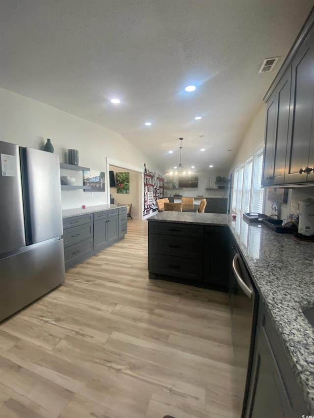 6205 Nixon St, North Myrtle Beach, SC 29582 - kitchen featuring appliances with stainless steel finishes, a peninsula, light wood-style flooring, light stone countertops, and vaulted ceiling