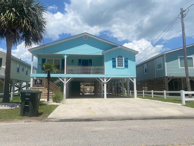6205 Nixon St, North Myrtle Beach, SC 29582 - raised beach house featuring driveway, fence, a carport, a porch, and stairway