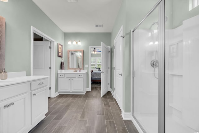ensuite bathroom with a ceiling fan, a stall shower, wood finished floors, vanity, and baseboards