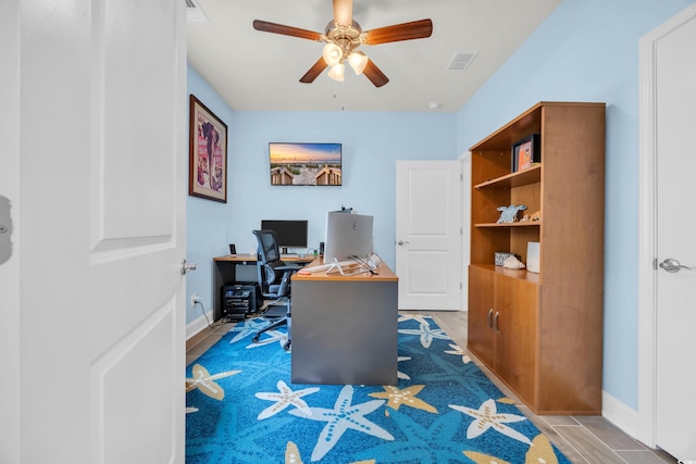 home office with a ceiling fan and baseboards