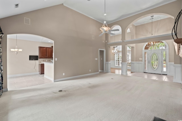 unfurnished living room featuring a chandelier, high vaulted ceiling, light tile patterned flooring, light carpet, and a ceiling fan