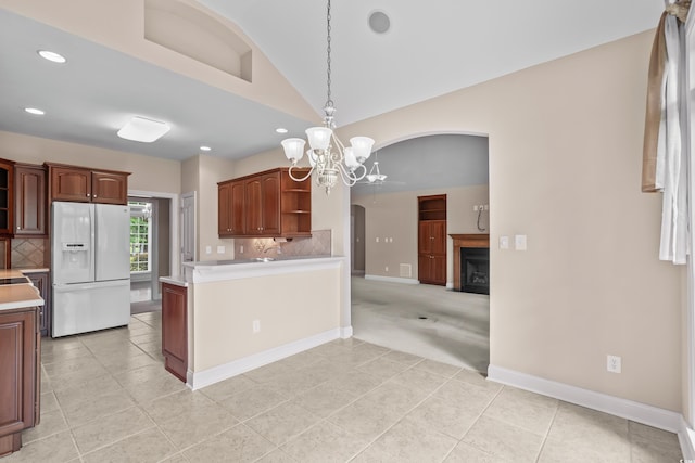 kitchen with white refrigerator with ice dispenser, open shelves, a chandelier, arched walkways, and light tile patterned floors