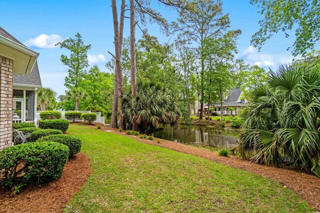 view of green lawn featuring a water view