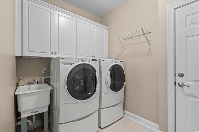 clothes washing area with independent washer and dryer, cabinet space, baseboards, and light tile patterned flooring