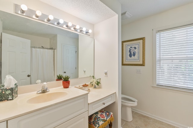 bathroom featuring healthy amount of natural light, tile patterned floors, toilet, and vanity