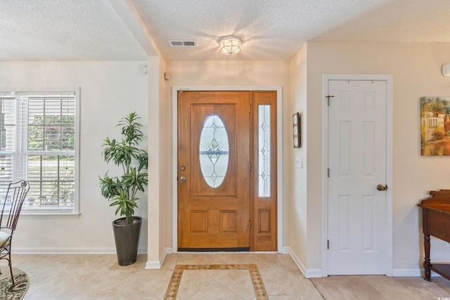 foyer with a textured ceiling, baseboards, and light tile patterned floors
