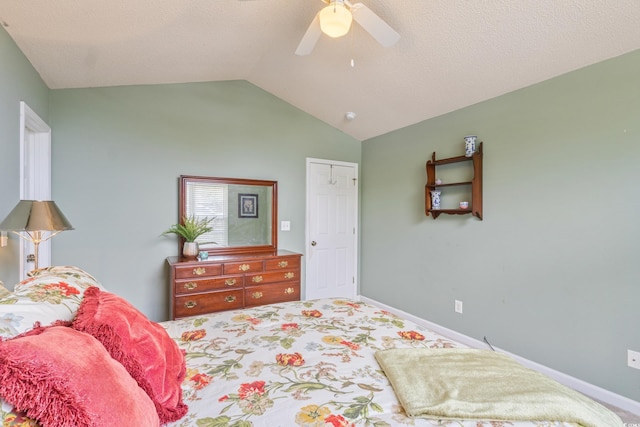 carpeted bedroom featuring vaulted ceiling, a ceiling fan, baseboards, and a textured ceiling