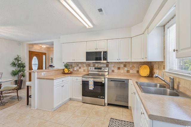 kitchen featuring stainless steel appliances, a sink, decorative backsplash, and white cabinets