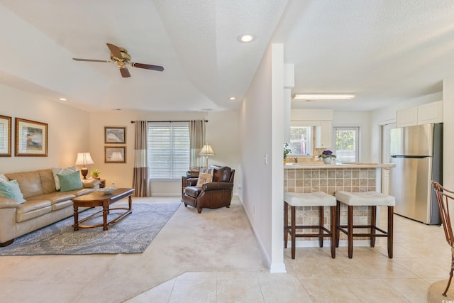 living area featuring ceiling fan, light tile patterned floors, light colored carpet, recessed lighting, and a textured ceiling