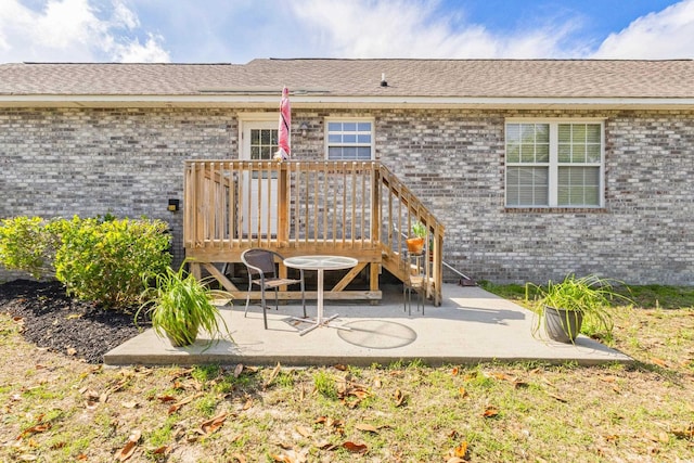 rear view of property featuring brick siding, a patio area, and a deck