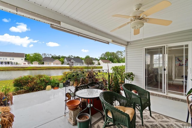 view of patio with a water view, ceiling fan, and a residential view