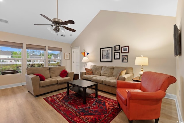 living area with ceiling fan, light wood finished floors, high vaulted ceiling, and baseboards