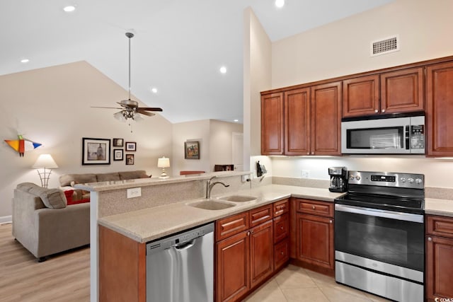 kitchen with stainless steel appliances, a sink, open floor plan, a peninsula, and a ceiling fan