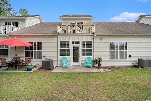 back of property with a balcony, a patio area, central AC unit, and a lawn