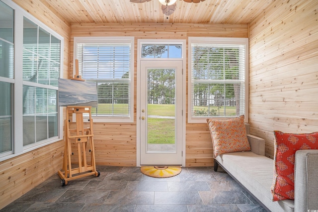 entryway featuring wooden walls, stone tile floors, plenty of natural light, ceiling fan, and wooden ceiling