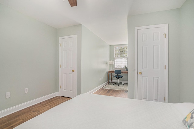 bedroom featuring wood finished floors, an office area, and baseboards