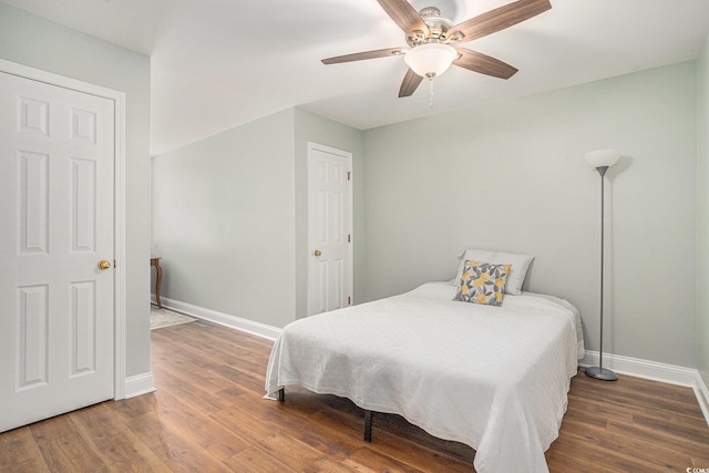 bedroom featuring baseboards, wood finished floors, and a ceiling fan