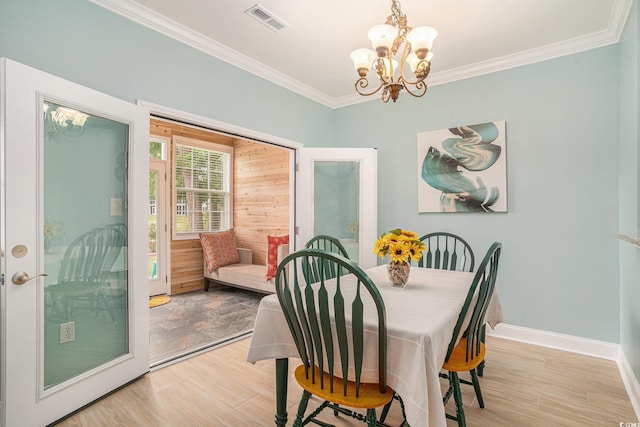 dining area featuring a chandelier, light wood-type flooring, crown molding, and baseboards