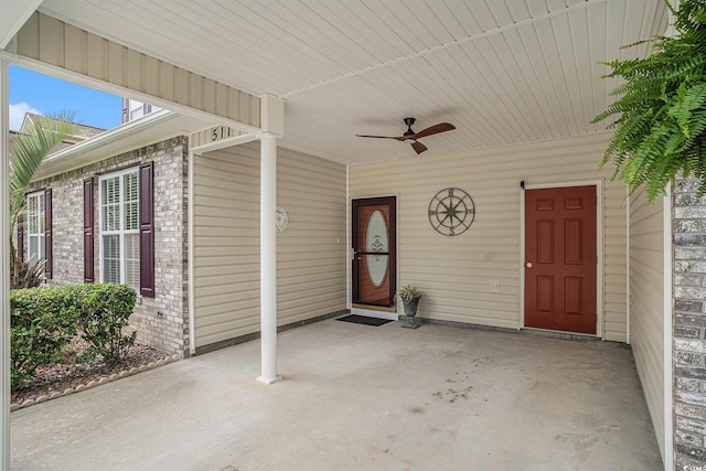 view of exterior entry with brick siding and a ceiling fan