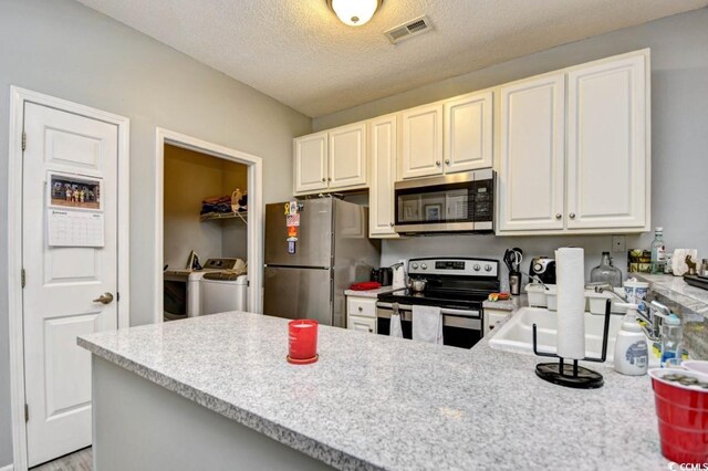 4811 Innisbrook Ct Unit 306, Myrtle Beach, SC 29579 - kitchen featuring stainless steel appliances, washer and clothes dryer, a peninsula, a textured ceiling, and white cabinetry
