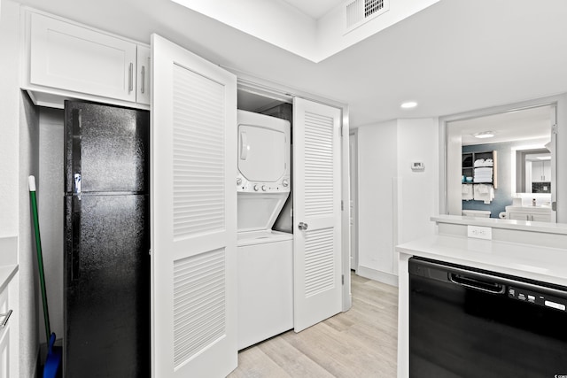 2301 S Ocean Blvd Unit 621, Myrtle Beach, SC 29577 - kitchen featuring stacked washer and clothes dryer, black appliances, light wood-style floors, light countertops, and white cabinetry