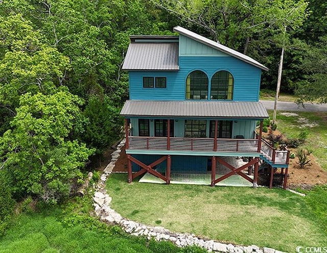 view of front of house featuring stairway, a porch, a wooded view, and a front yard