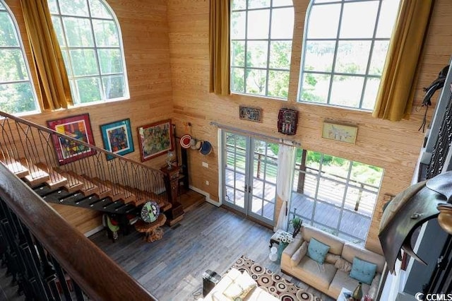 living room featuring stairway, wooden walls, french doors, and wood finished floors