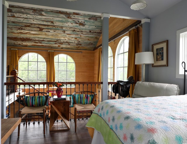 bedroom featuring multiple windows, lofted ceiling, wood walls, and wood finished floors