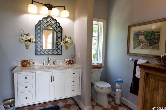 bathroom with toilet, vanity, and baseboards