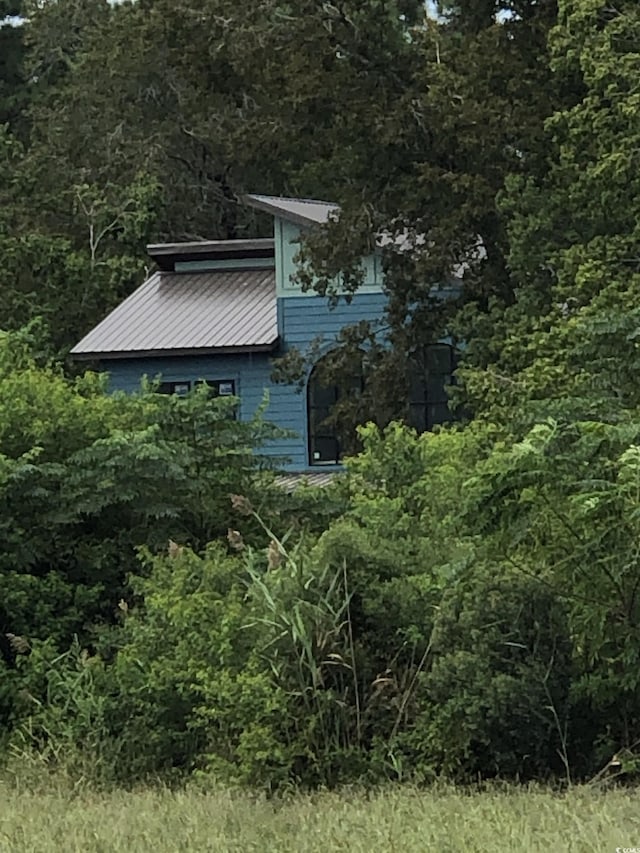 view of side of home with a view of trees and metal roof