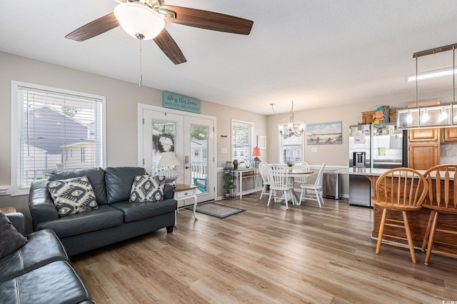 living room featuring light wood-style floors, healthy amount of natural light, a chandelier, and ceiling fan