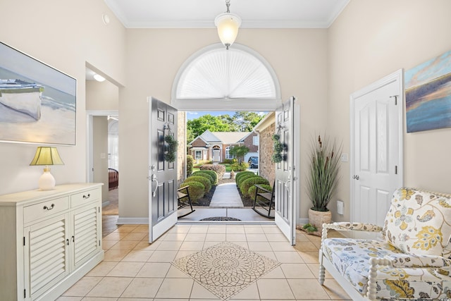 foyer featuring a high ceiling, light tile patterned floors, baseboards, and ornamental molding