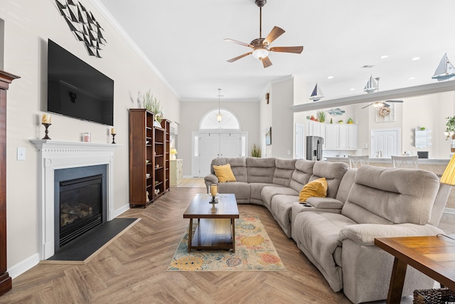 living room featuring a ceiling fan, baseboards, crown molding, recessed lighting, and a glass covered fireplace
