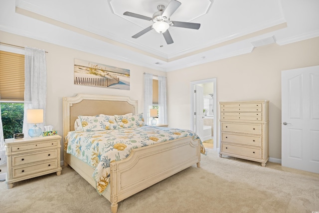 bedroom with a tray ceiling, ornamental molding, light colored carpet, multiple windows, and ensuite bathroom