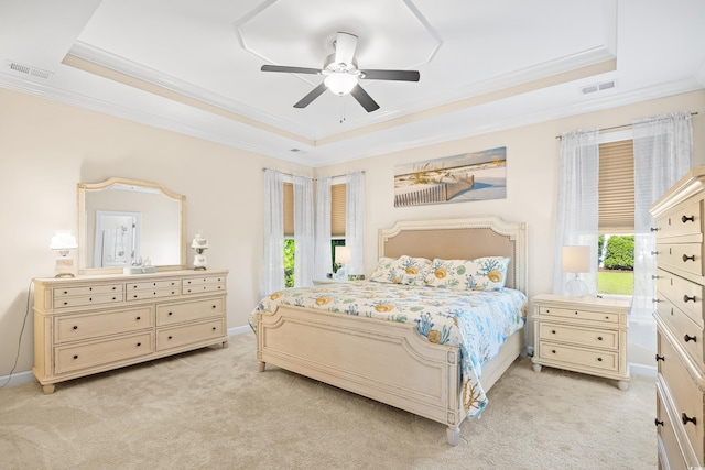 bedroom featuring a tray ceiling, ornamental molding, light carpet, a ceiling fan, and baseboards