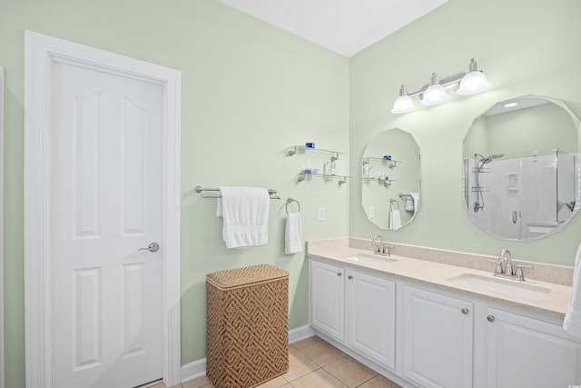 full bathroom with tile patterned floors, baseboards, double vanity, and a shower