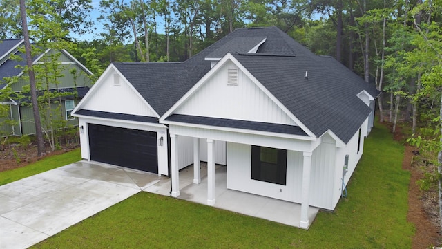 4120 Whatuthink Rd, Myrtle Beach, SC 29588 - modern farmhouse featuring roof with shingles, a front lawn, driveway, an attached garage, and covered porch