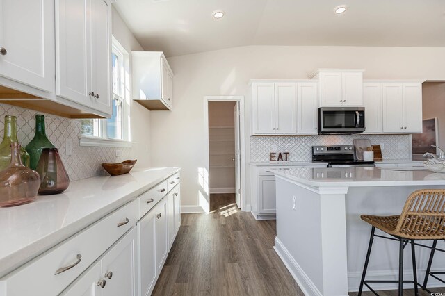 764 Choctaw Dr, Conway, SC 29526 - kitchen featuring appliances with stainless steel finishes, dark wood-type flooring, a kitchen breakfast bar, light countertops, and decorative backsplash