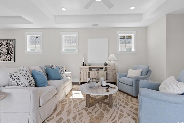 living room featuring a tray ceiling, healthy amount of natural light, ceiling fan, and recessed lighting