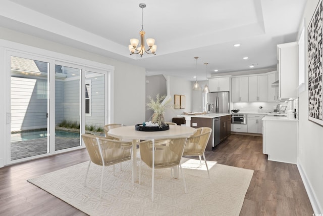 dining area with a chandelier, recessed lighting, dark wood-style flooring, and a tray ceiling