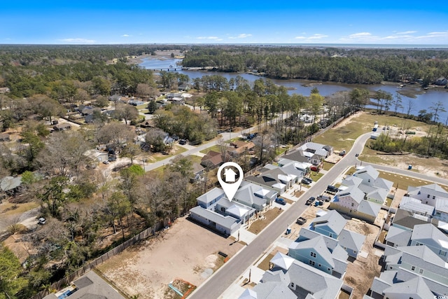 aerial overview of property's location with a nearby body of water, a forest, and nearby suburban area