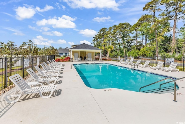 1340 Jolly Roger Dr, North Myrtle Beach, SC 29582 - community pool with a patio area, fence, and view of wooded area