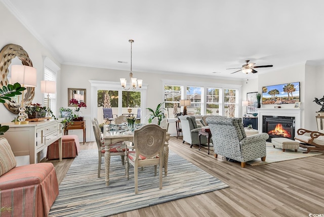 1340 Jolly Roger Dr, North Myrtle Beach, SC 29582 - dining room with crown molding, light wood-style flooring, a chandelier, a glass covered fireplace, and plenty of natural light