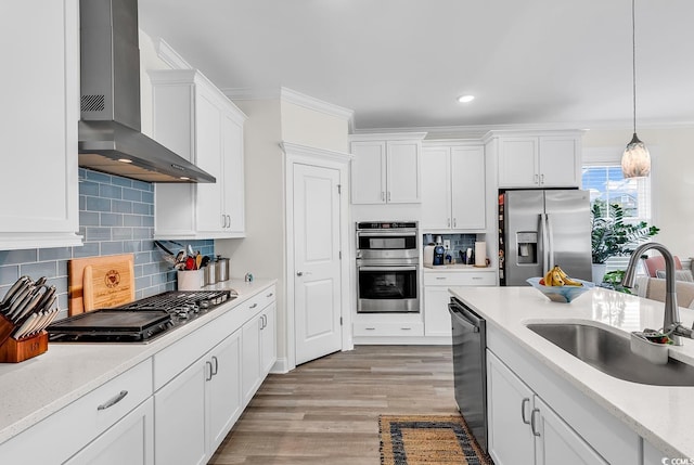 1340 Jolly Roger Dr, North Myrtle Beach, SC 29582 - kitchen featuring appliances with stainless steel finishes, wall chimney range hood, a sink, white cabinets, and ornamental molding