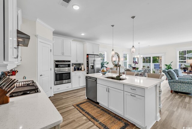 1340 Jolly Roger Dr, North Myrtle Beach, SC 29582 - kitchen featuring appliances with stainless steel finishes, a sink, open floor plan, light wood finished floors, and white cabinetry